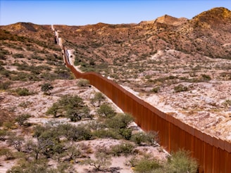 A long metal fence in the middle of a desert