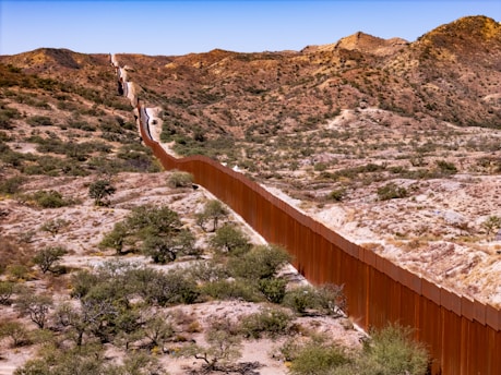 A long metal fence in the middle of a desert