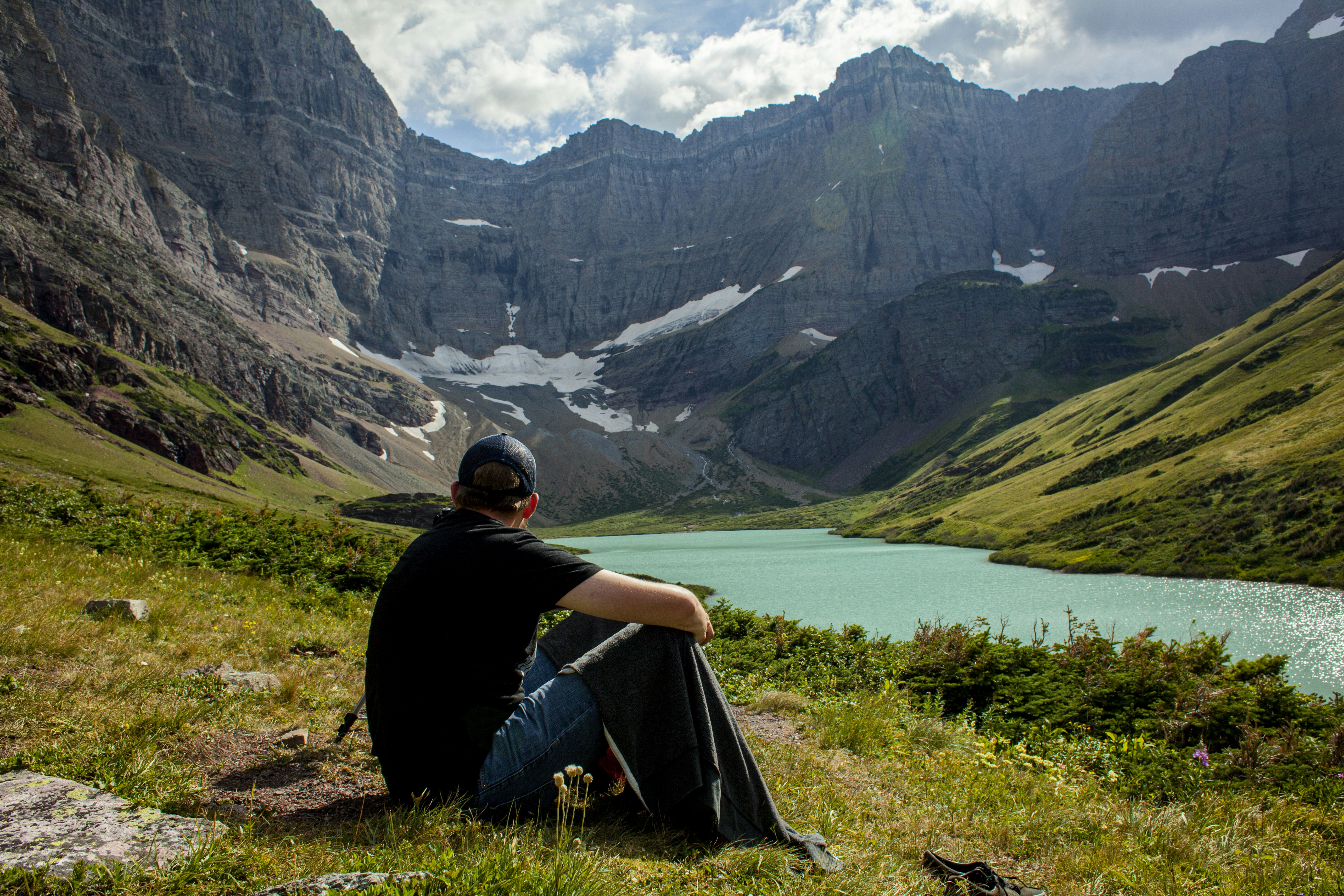 Ein Mann sitzt an der Seite eines Berges neben einem See