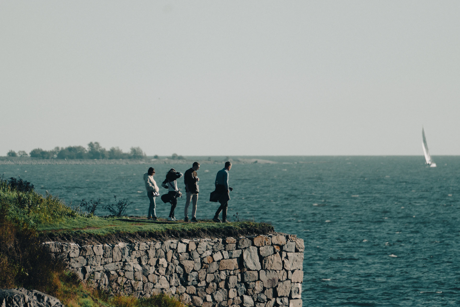 A group of people standing on top of a cliff next to the ocean