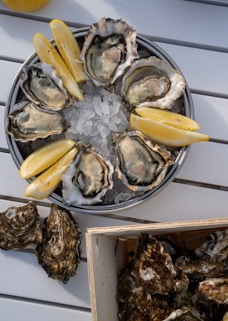 A plate of oysters with lemon wedges and a box of oysters