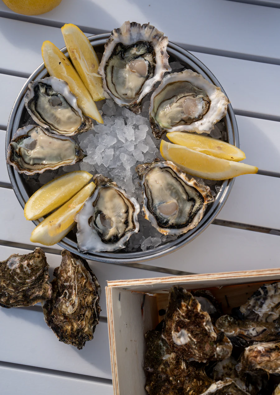 A plate of fresh oysters with lemon wedges