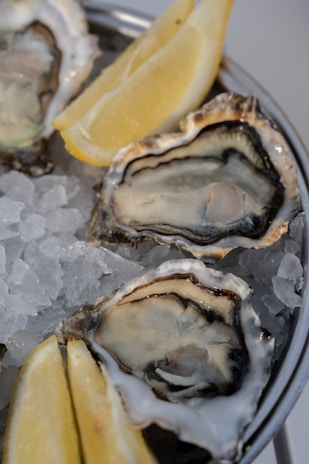A metal pan filled with oysters and lemon wedges