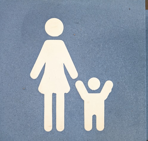 A blue sign with a white silhouette of a woman holding a child's hand