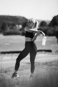 A woman standing in a field holding a drink