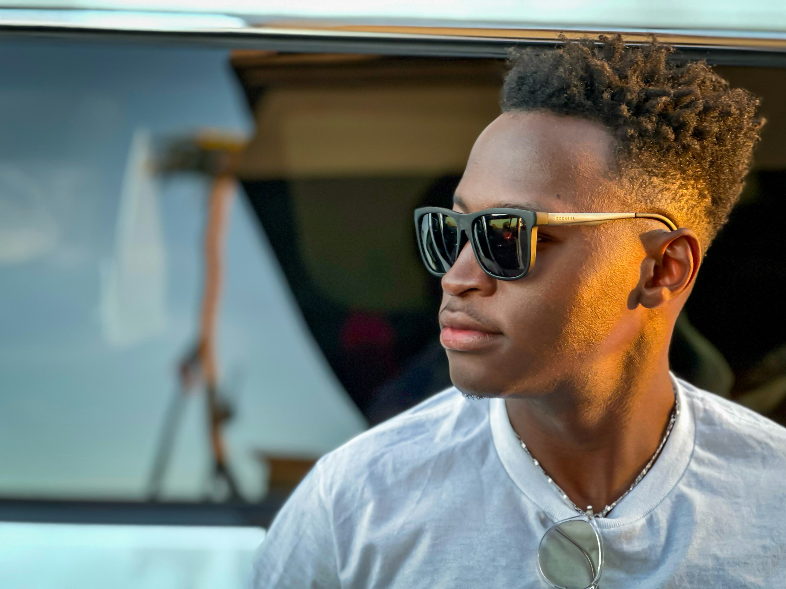 A man wearing sunglasses and a tie standing in front of a car