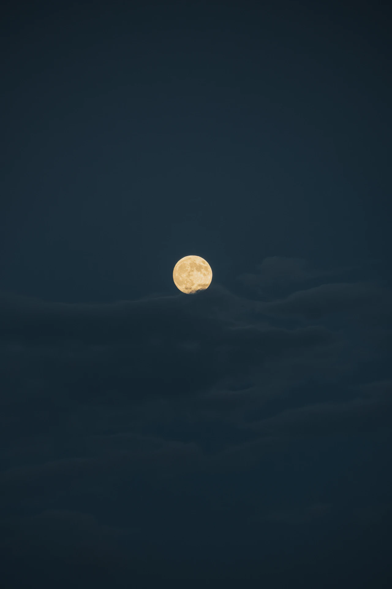 Full moon glowing through clouds over the city at night