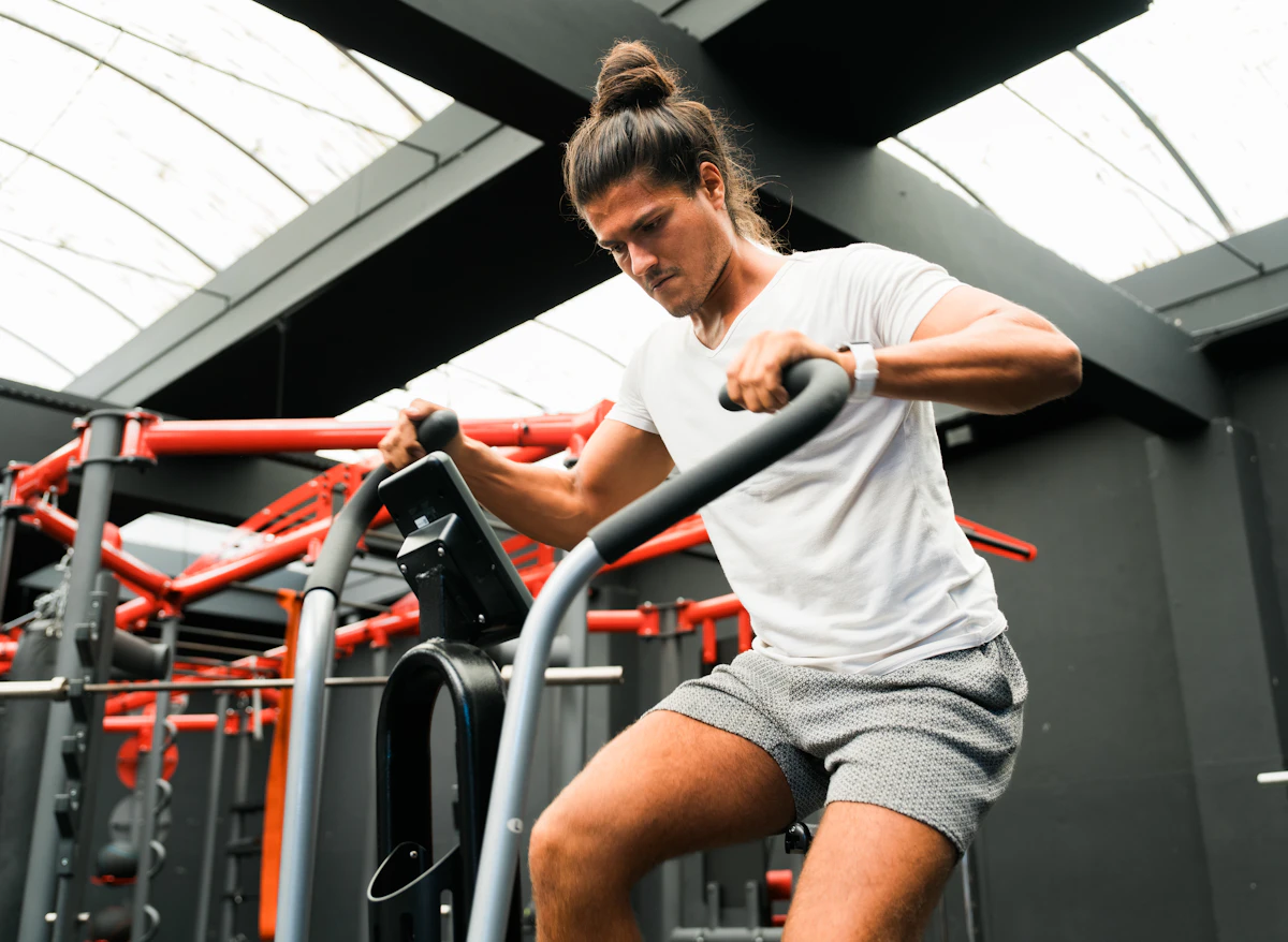 Man training on a gym machine while wearing a fitness watch, illustrating a peptide therapy and biohacking recovery routine.