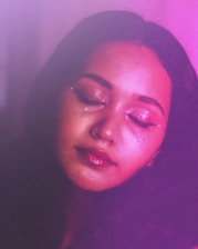 A woman with her eyes closed in a dark room