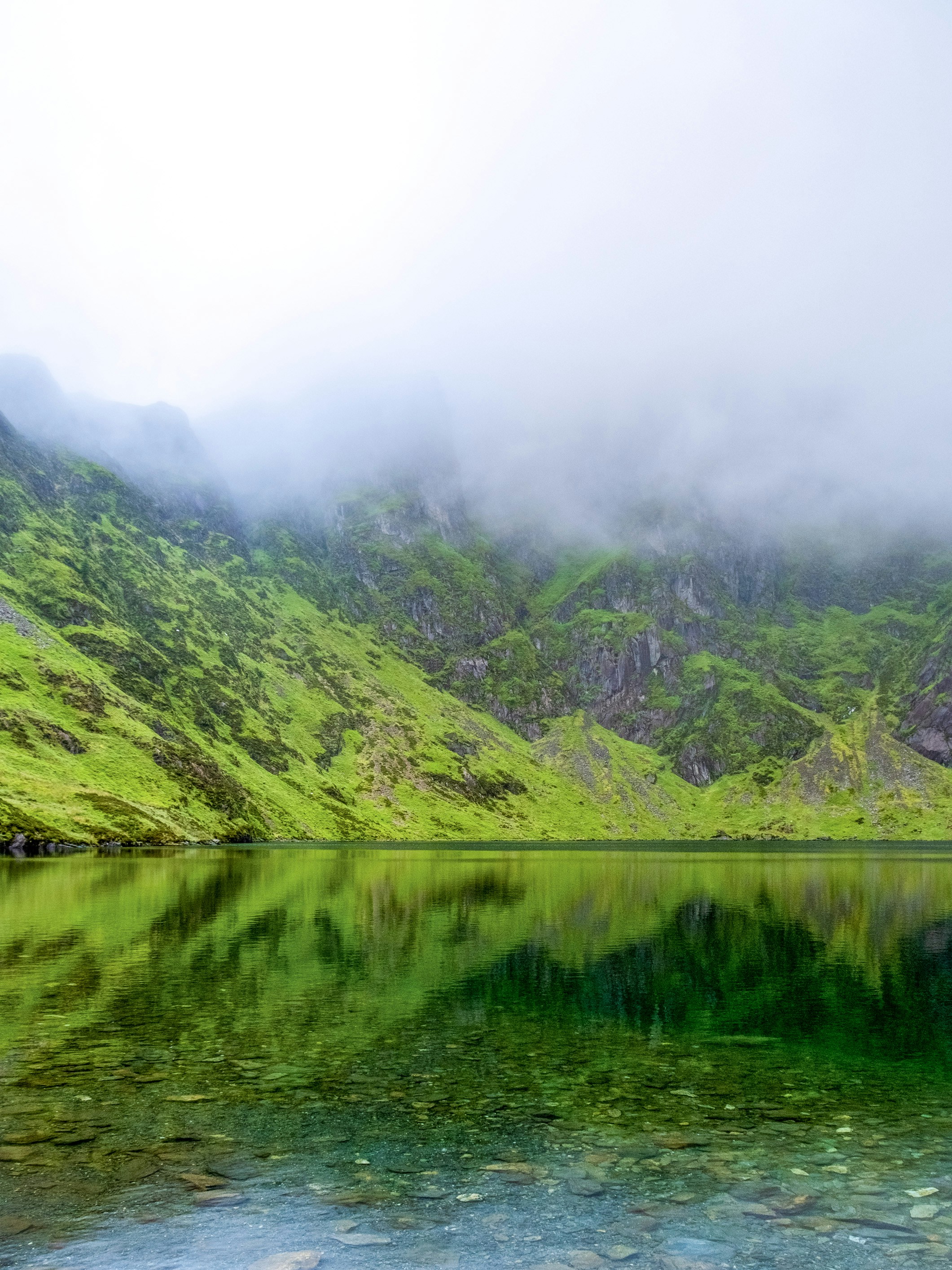 A body of water surrounded by green mountains