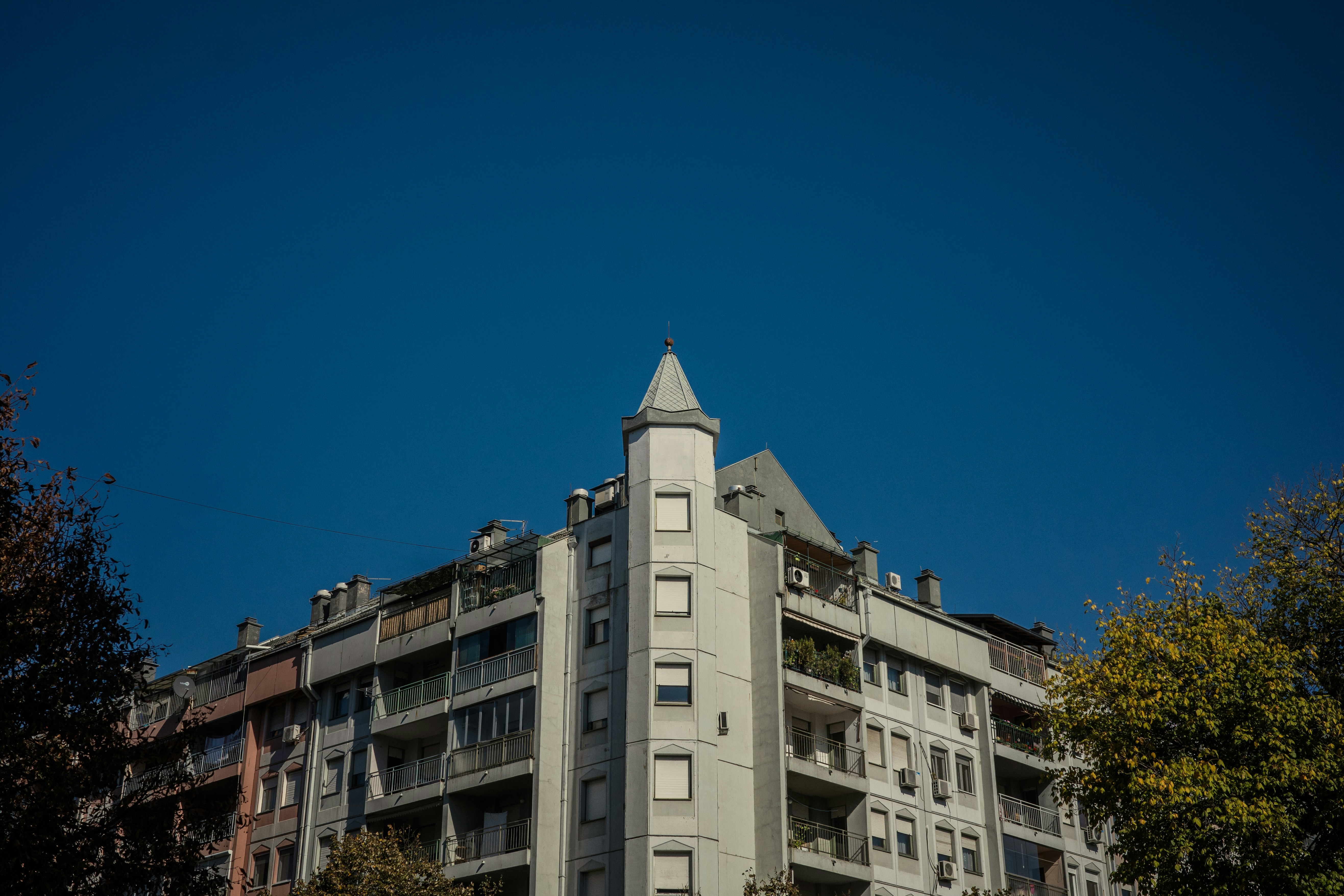 A tall building sitting next to a lush green forest, 