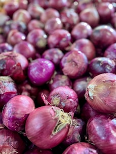 A pile of red onions sitting next to each other