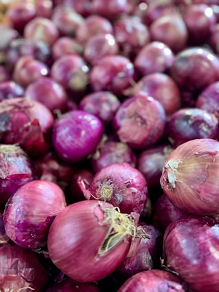 A pile of red onions sitting next to each other