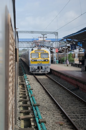 A yellow and white train traveling down train tracks