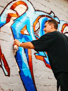 A man spray painting a wall with graffiti