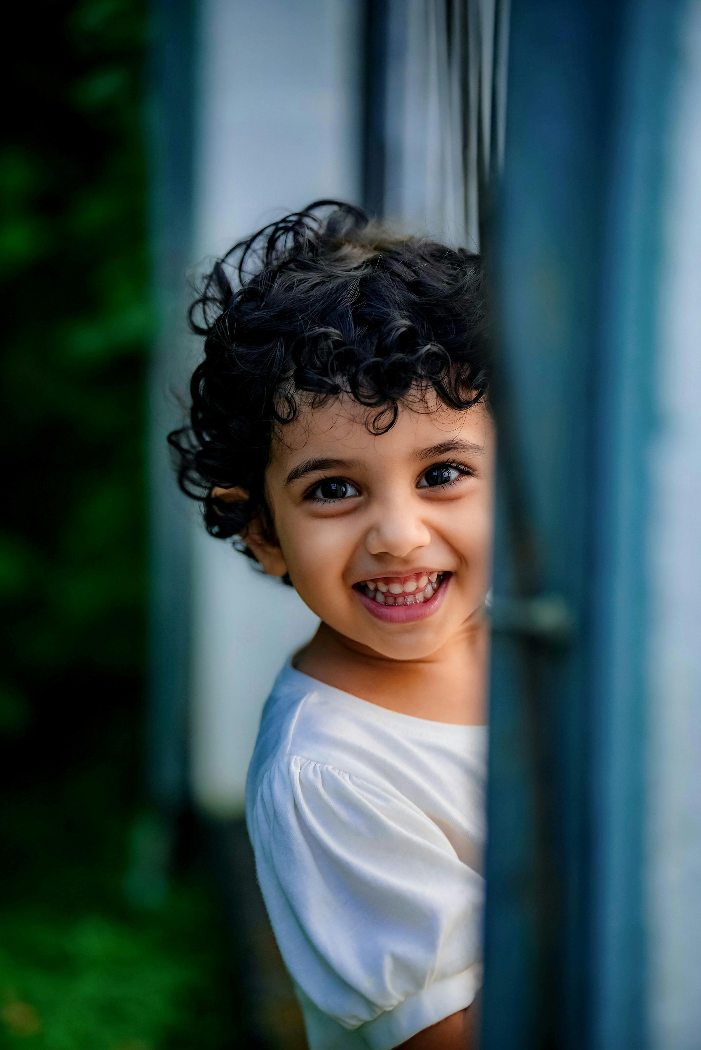 Une petite fille sourit en regardant par la fenêtre