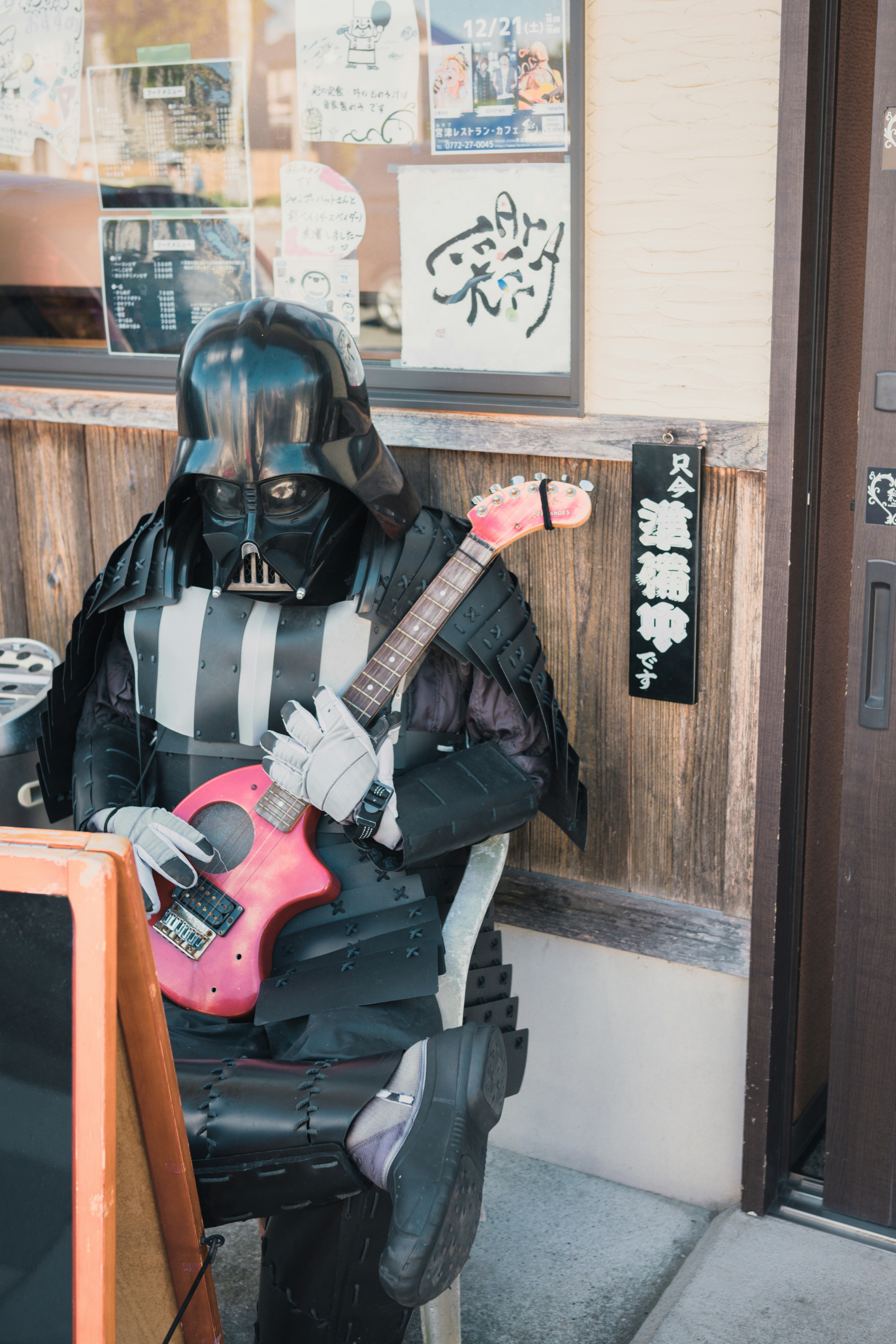 Seorang pria dengan pakaian darth vader bermain gitar