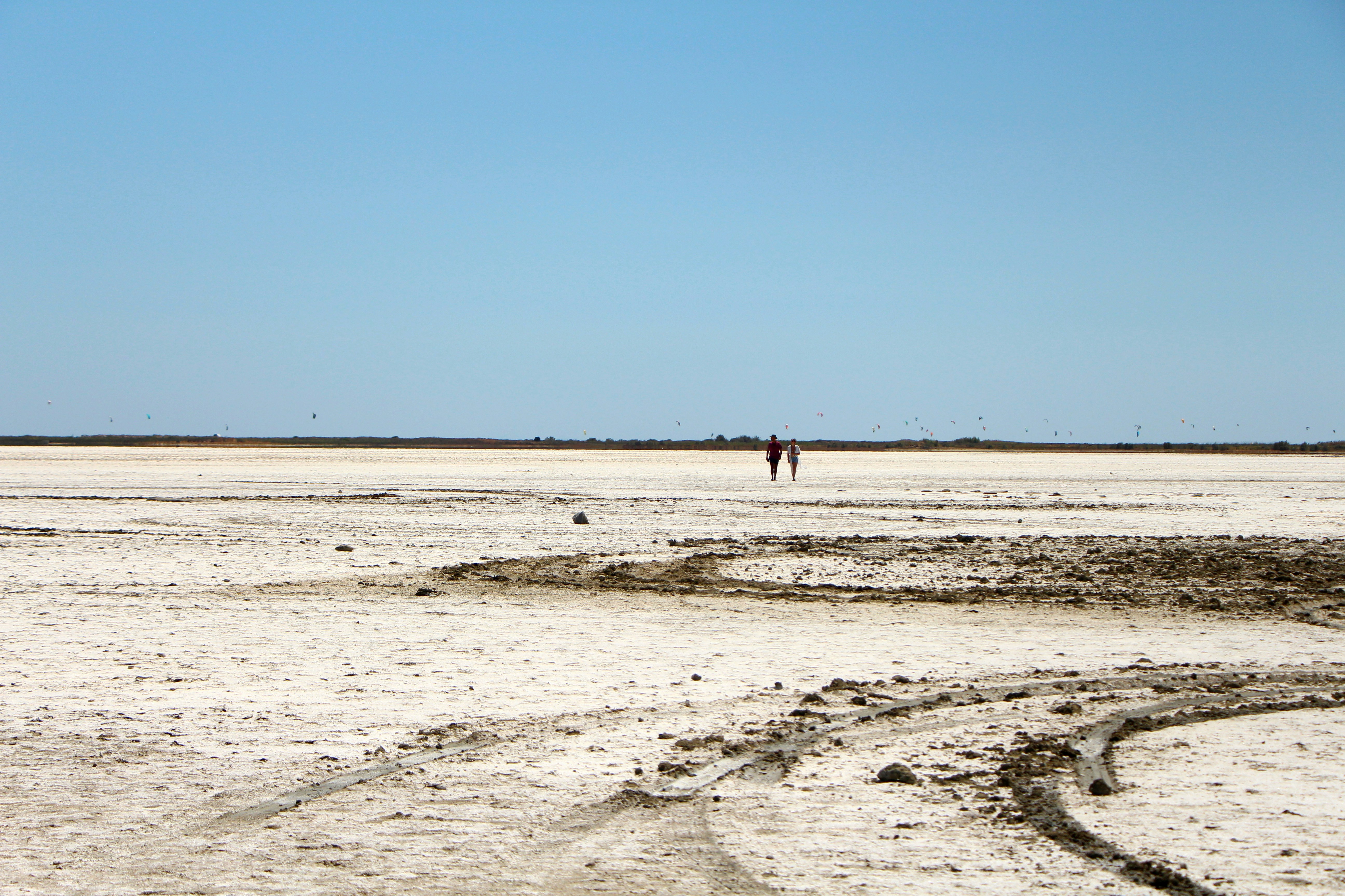 A couple of people walking across a sandy field