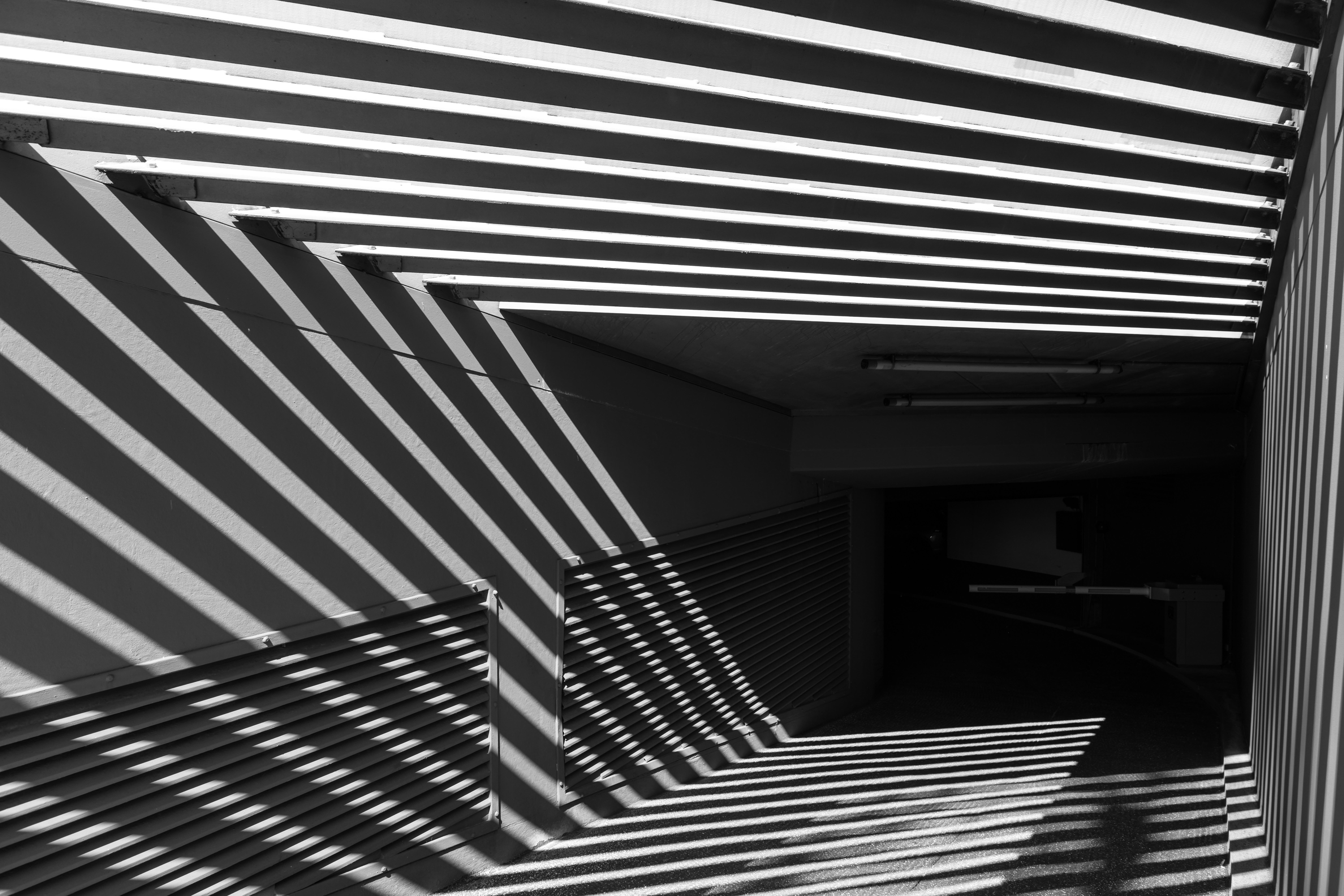 A precisely ordered architectural passage moves from clear illumination into an unresolved dark continuation, suggesting that one consequential part remains unseen before the next move can be chosen.