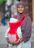 A woman in a hijab holding a baby in a sling