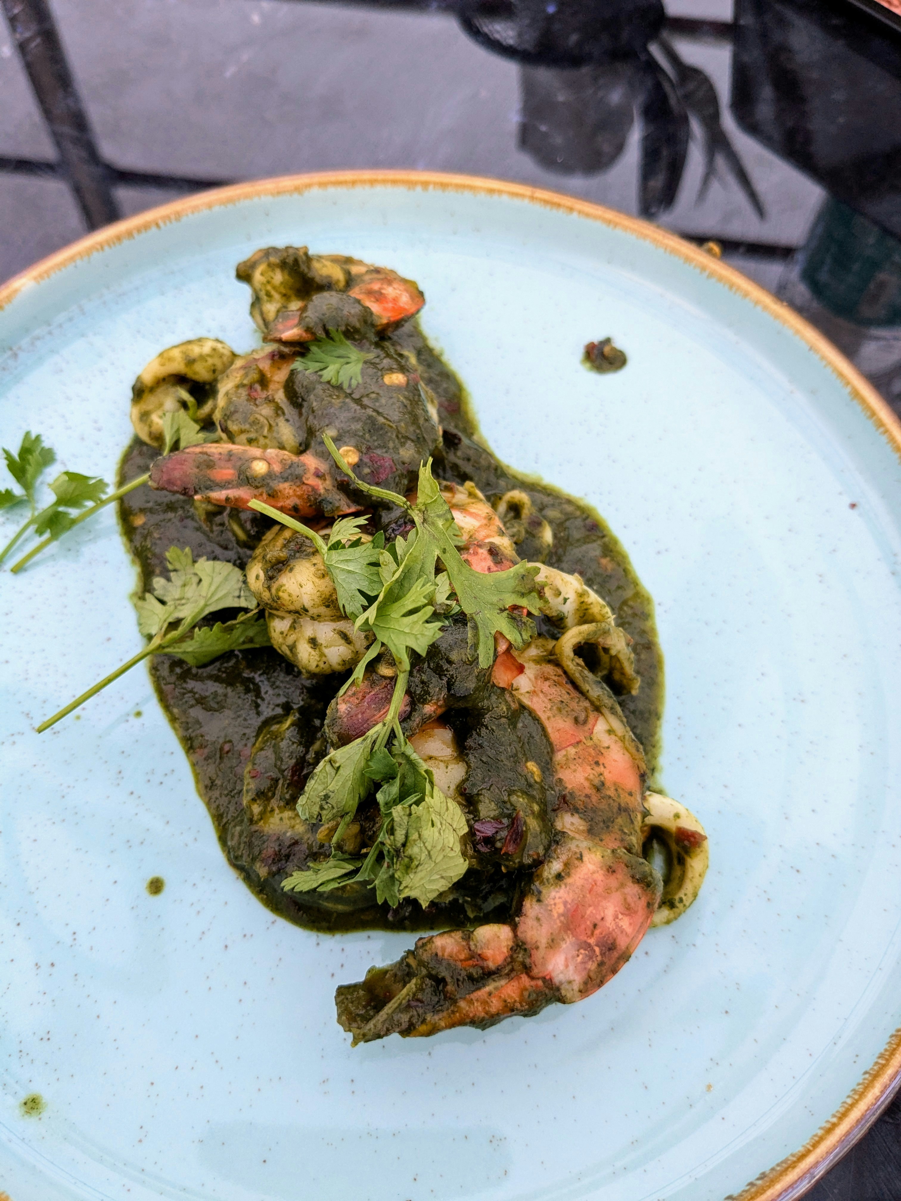 Vibrant green aguachile with fresh shrimp in white bowl, lime slices, dark wooden surface