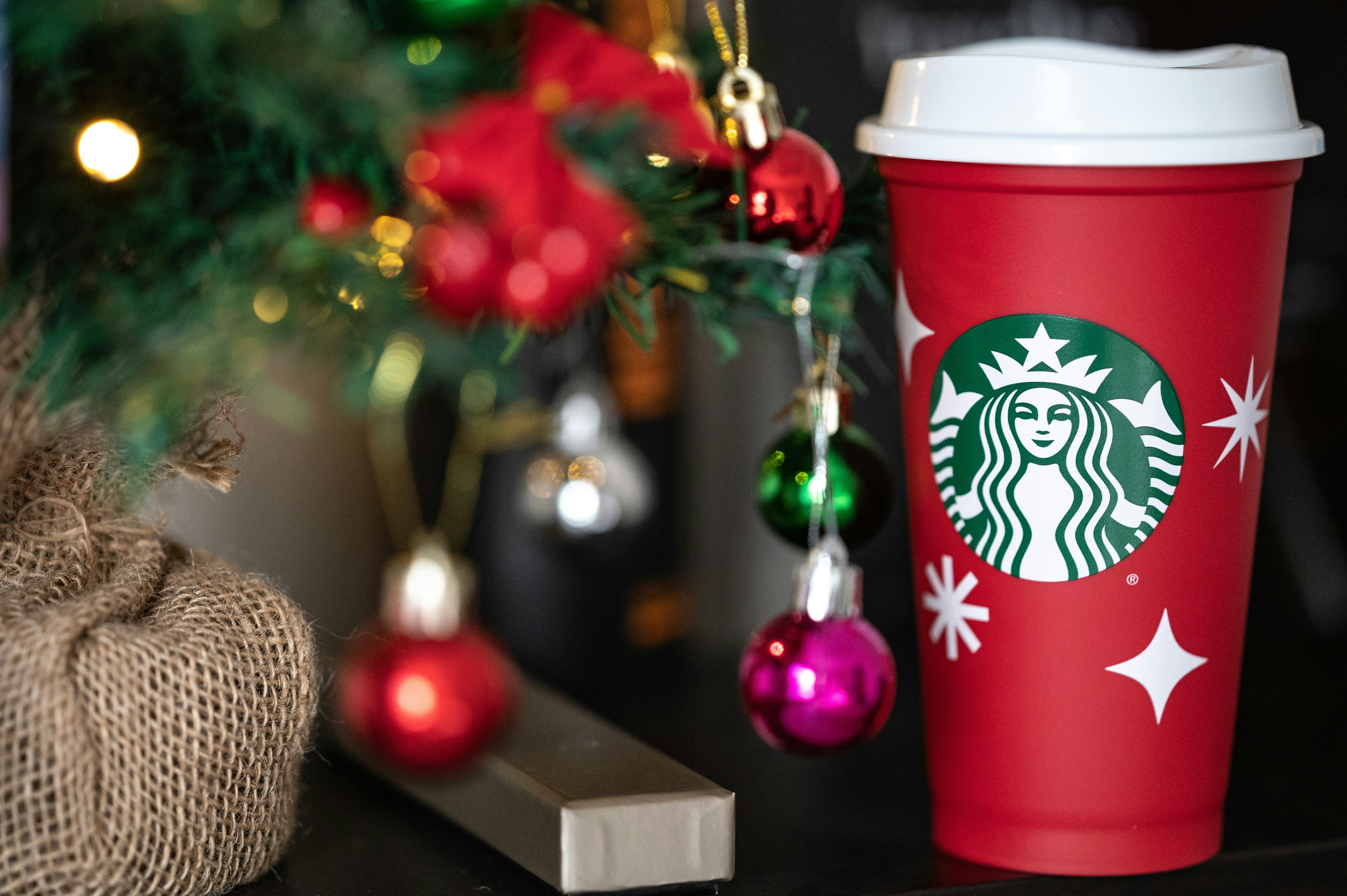 Una taza roja de Starbucks sentada junto a un árbol de Navidad