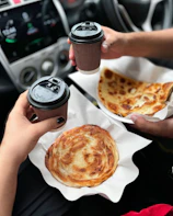 A person holding a cup of coffee and a plate of food