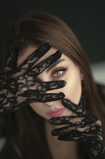 A woman with black gloves covering her face