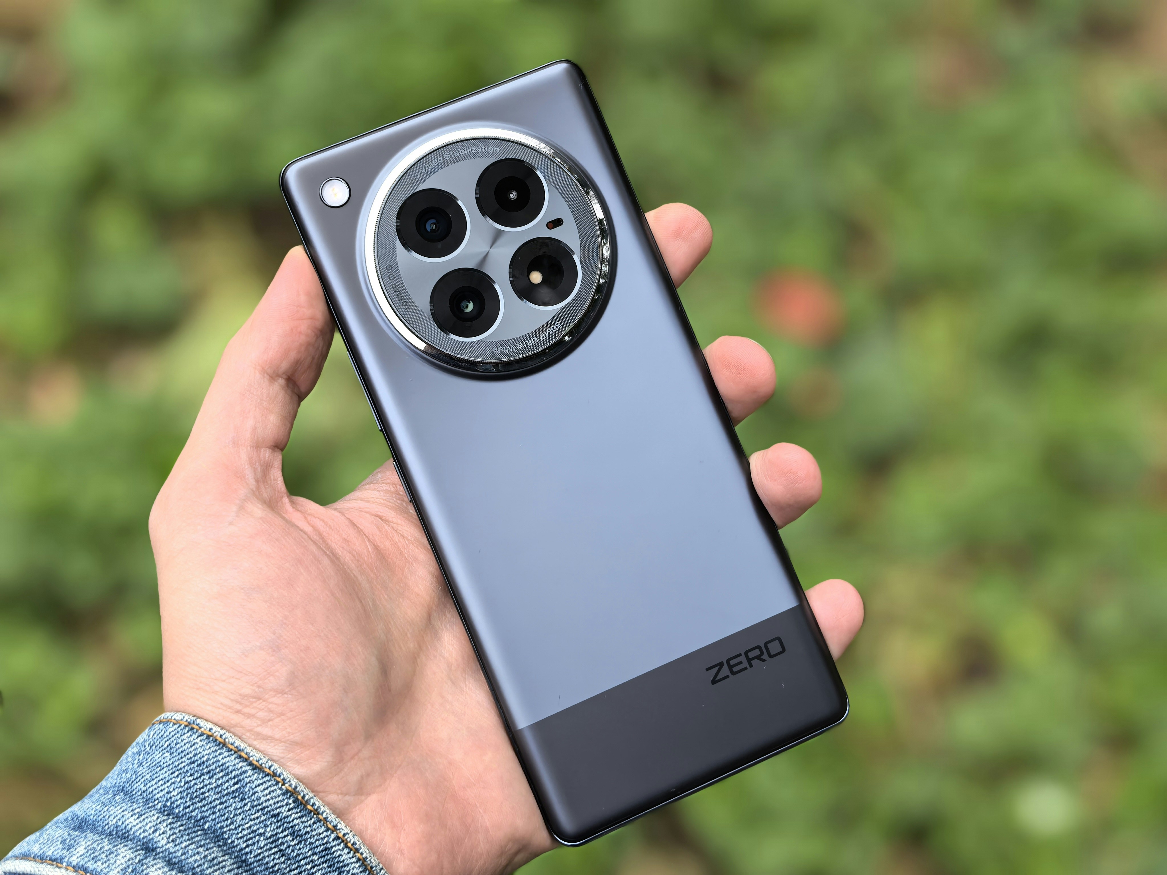 hands holding sleek dark titanium smartphone with variable aperture camera