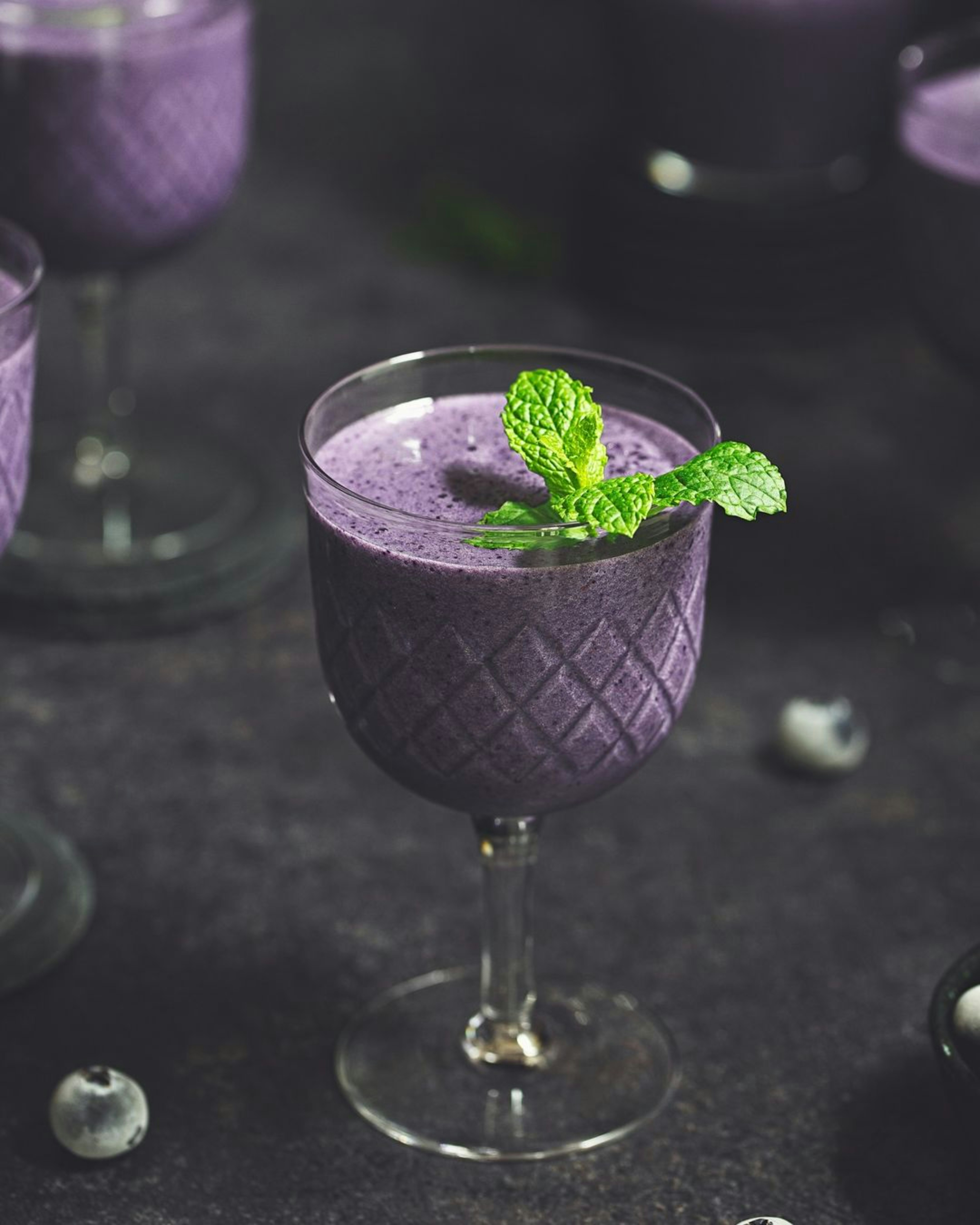 A purple drink with a mint garnish in a glass