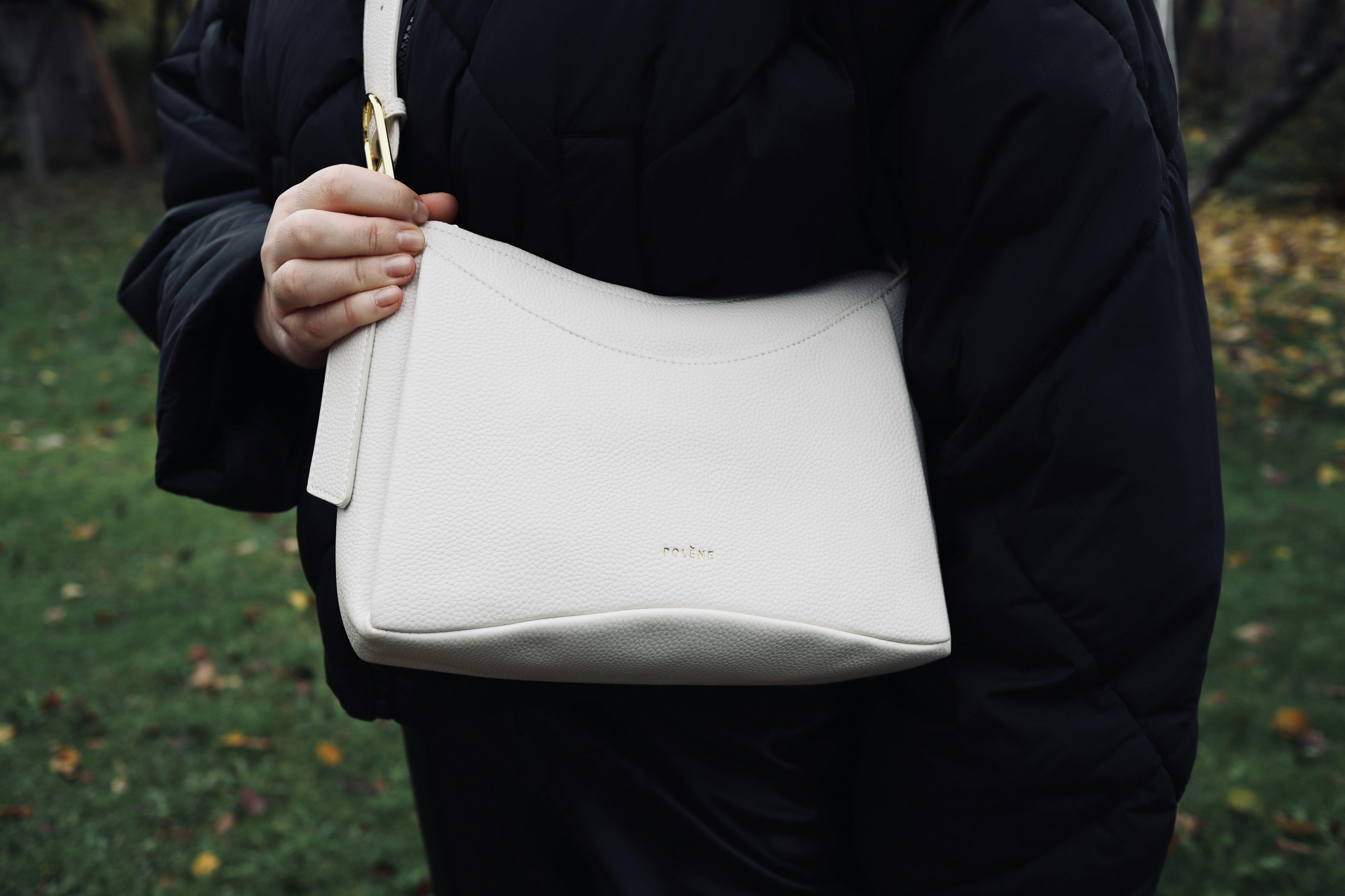 A woman holding a white purse in her hands