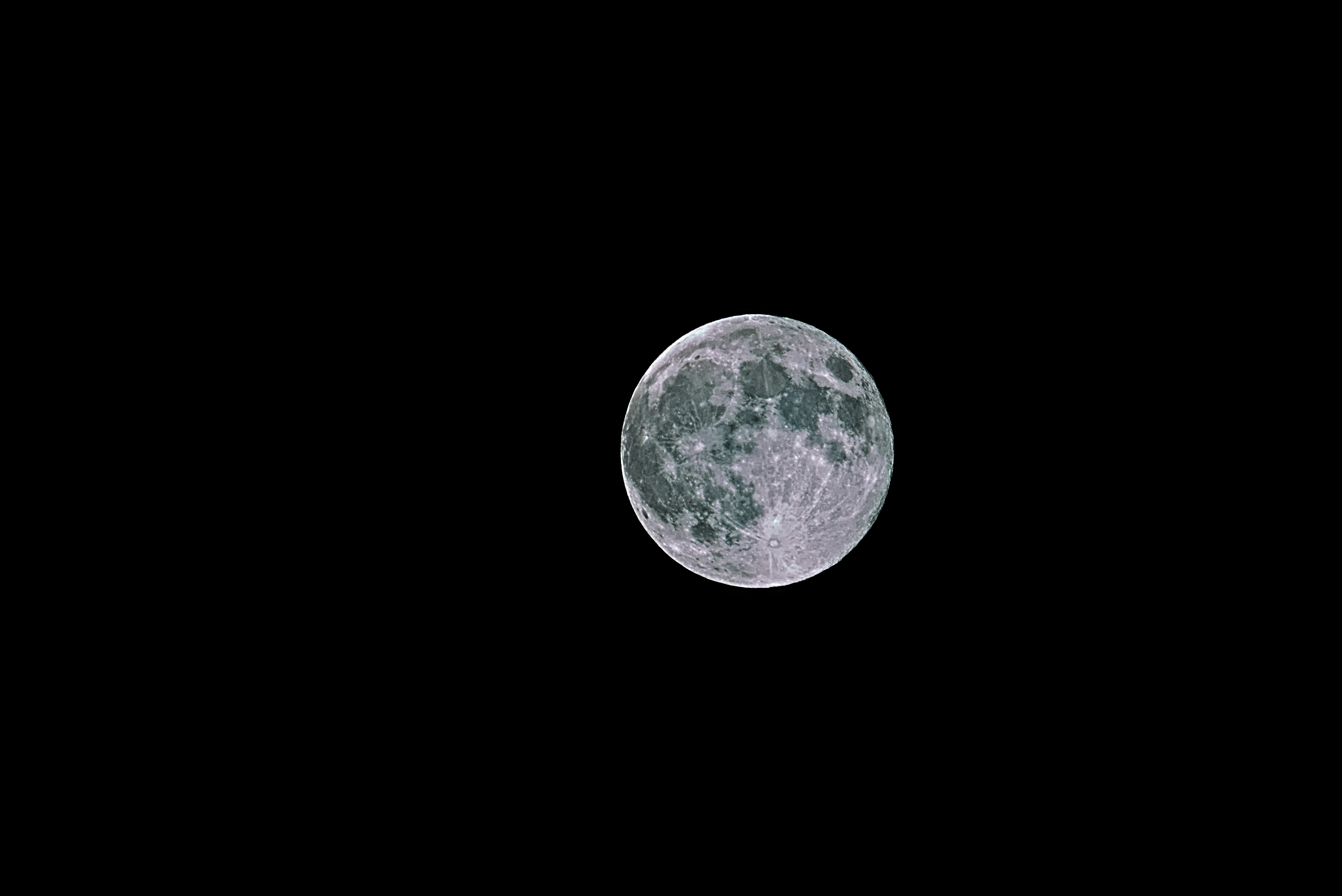 Une pleine lune est vue dans le ciel sombre