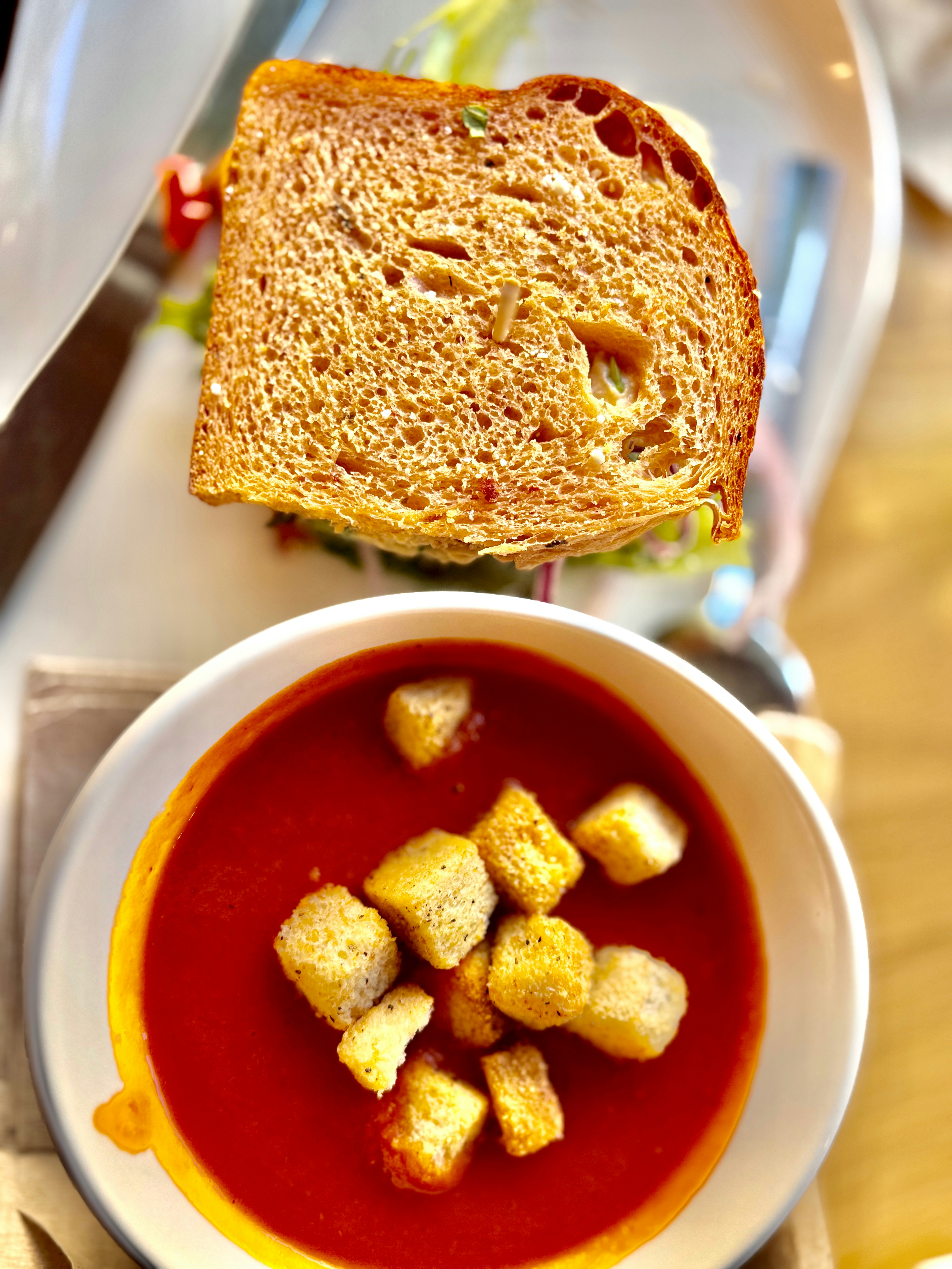 A bowl of soup and a sandwich on a table