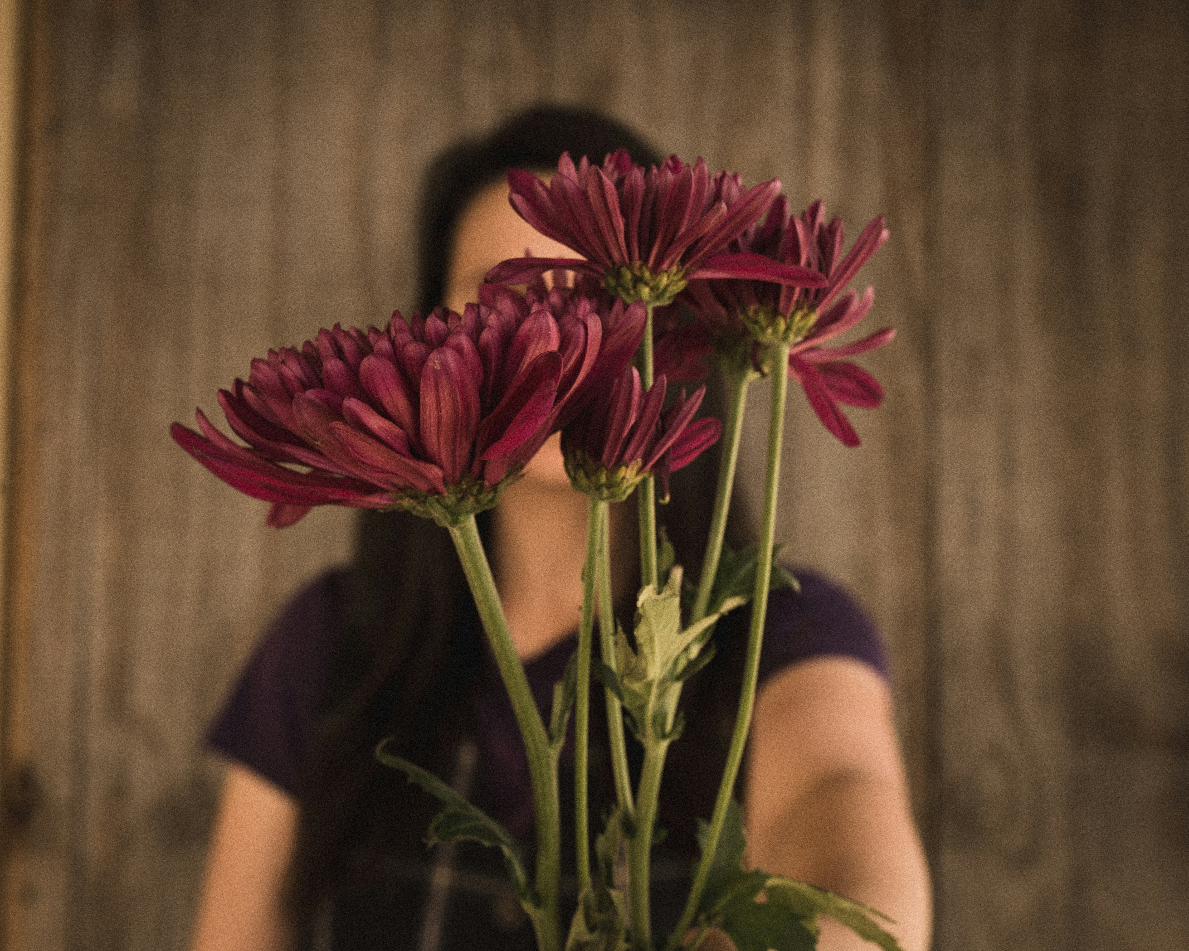 A woman holding a bouquet of flowers in front of her face