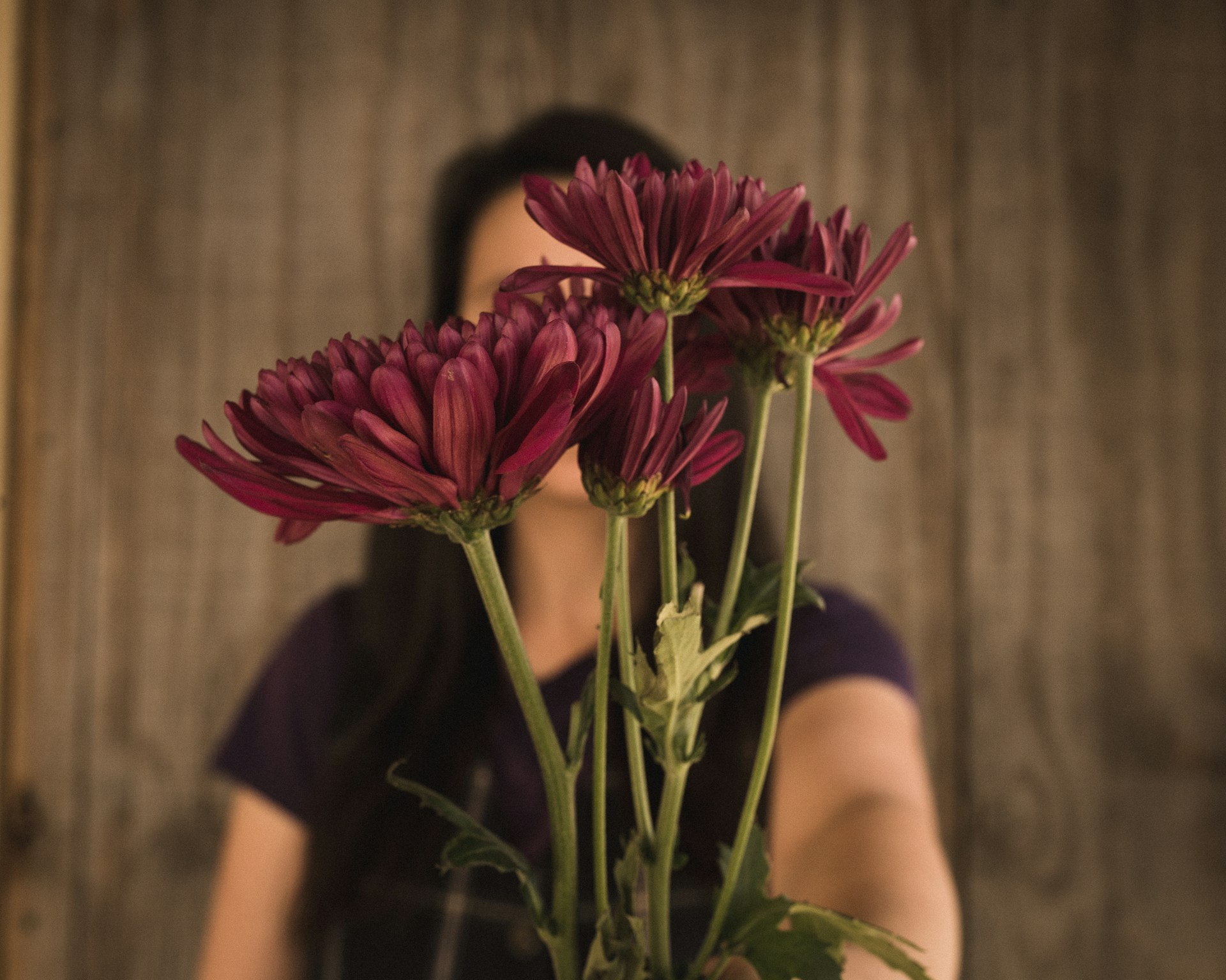 A woman holding a bouquet of flowers in front of her face