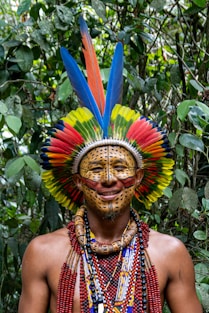 A man wearing a colorful headdress in a forest