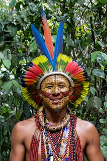 A man wearing a colorful headdress in a forest