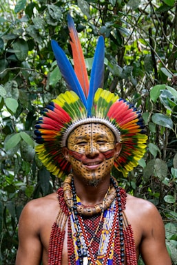 A man wearing a colorful headdress in a forest