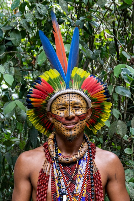 A man wearing a colorful headdress in a forest
