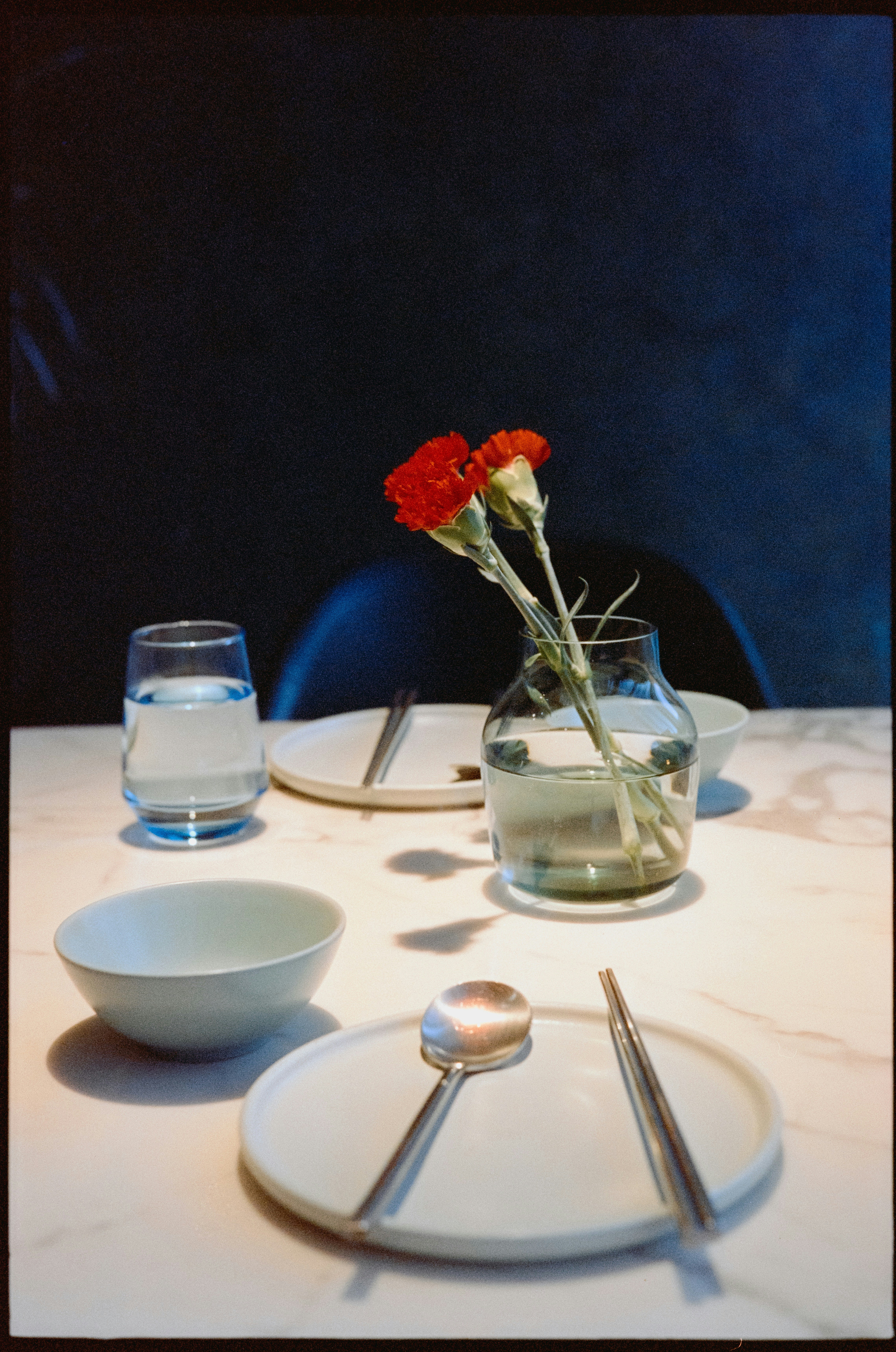 A white table topped with a bowl of water and a vase filled with flowers