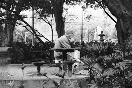 A black and white photo of a man sitting on a bench