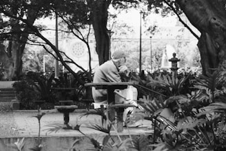 A black and white photo of a man sitting on a bench