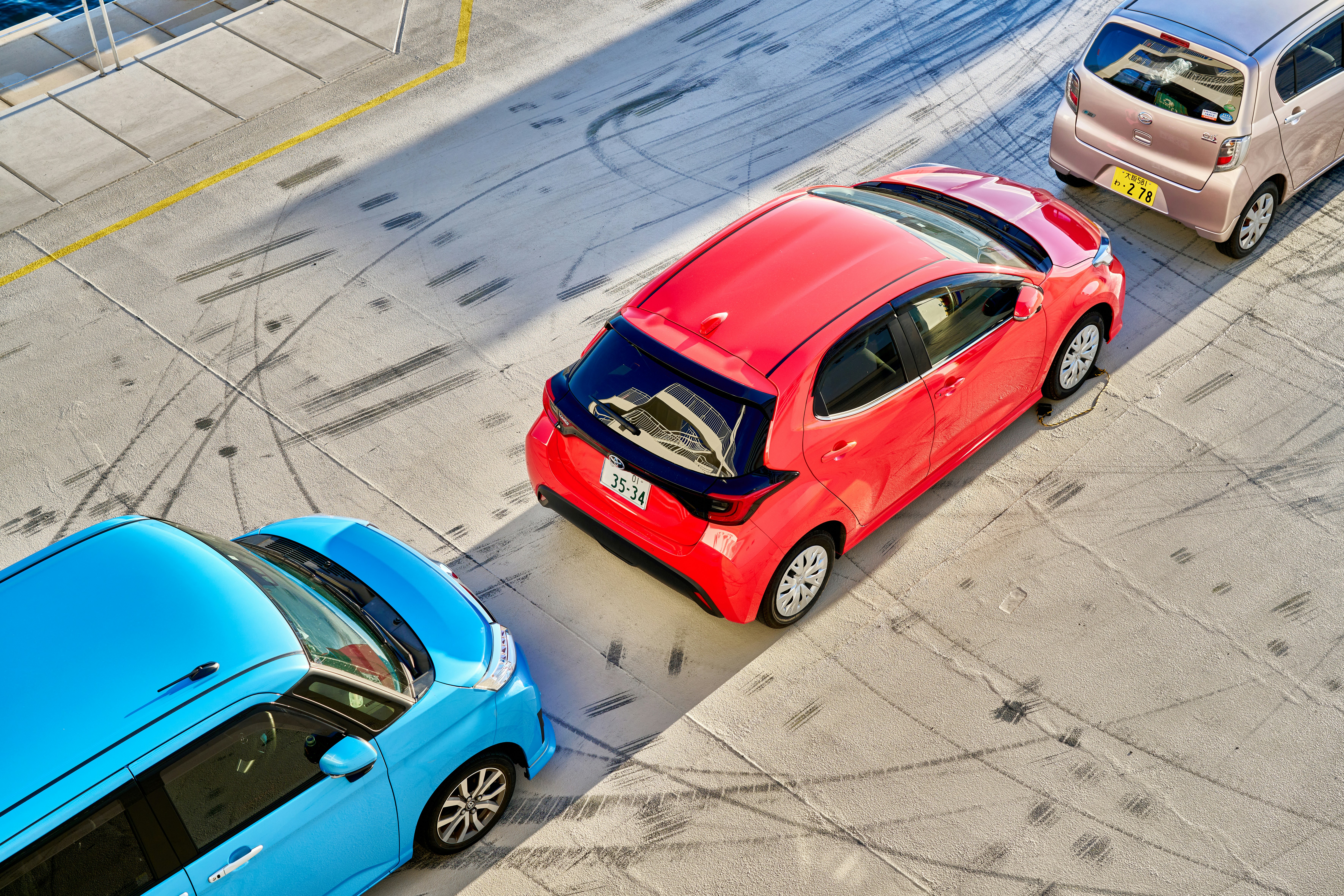 Three different colored cars driving down a street