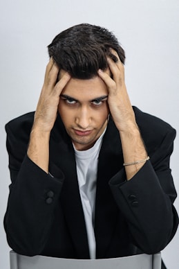 A man sitting at a desk with his hands on his head