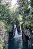 A waterfall in the middle of a river surrounded by trees