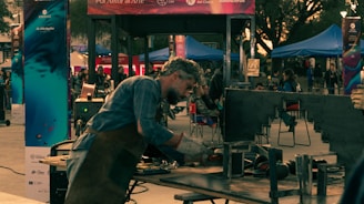 A man in a blue shirt is cooking on a grill