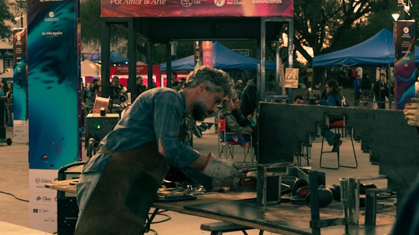 A man in a blue shirt is cooking on a grill