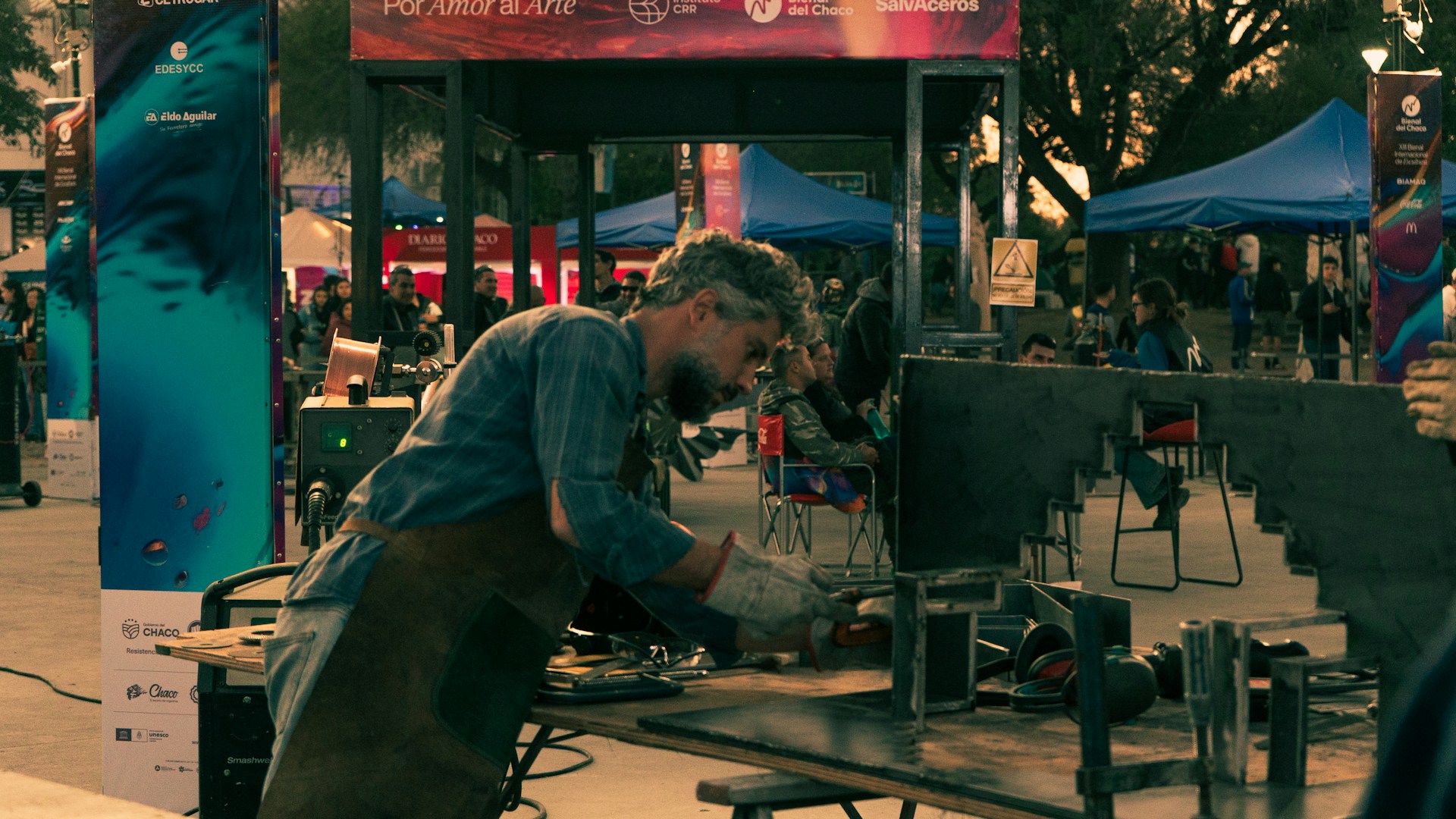 A man in a blue shirt is cooking on a grill