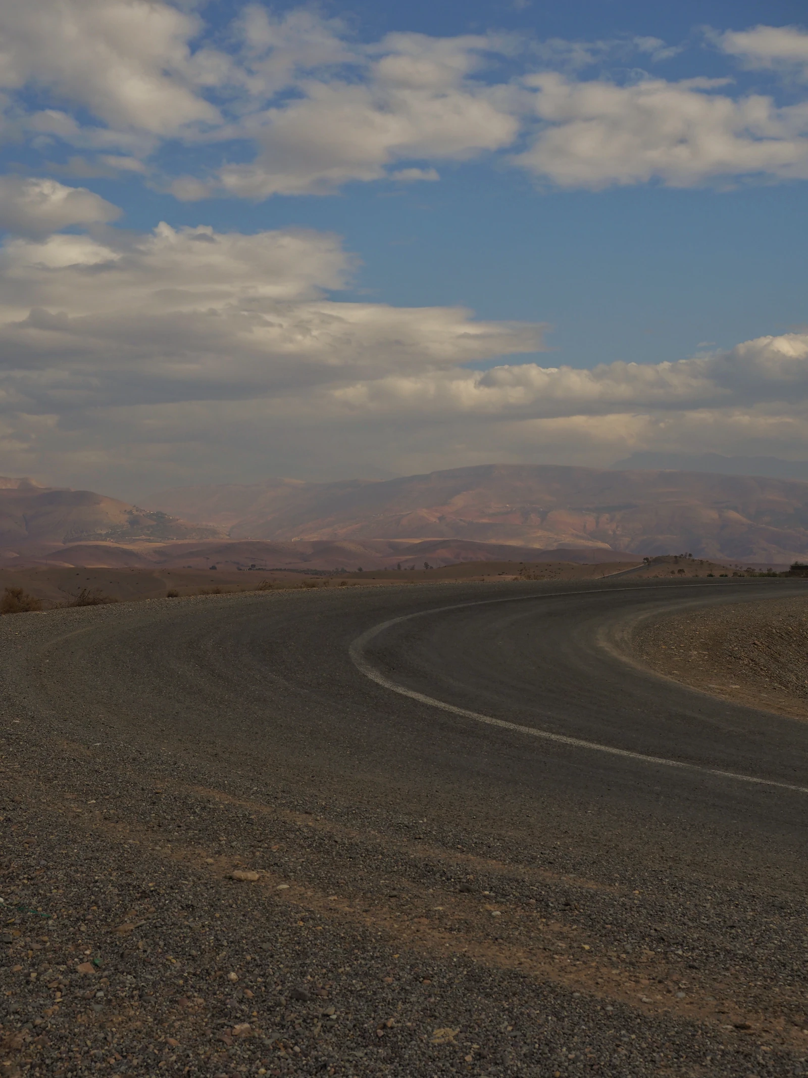 A Moroccan stop sign beside a road leading toward the mountains