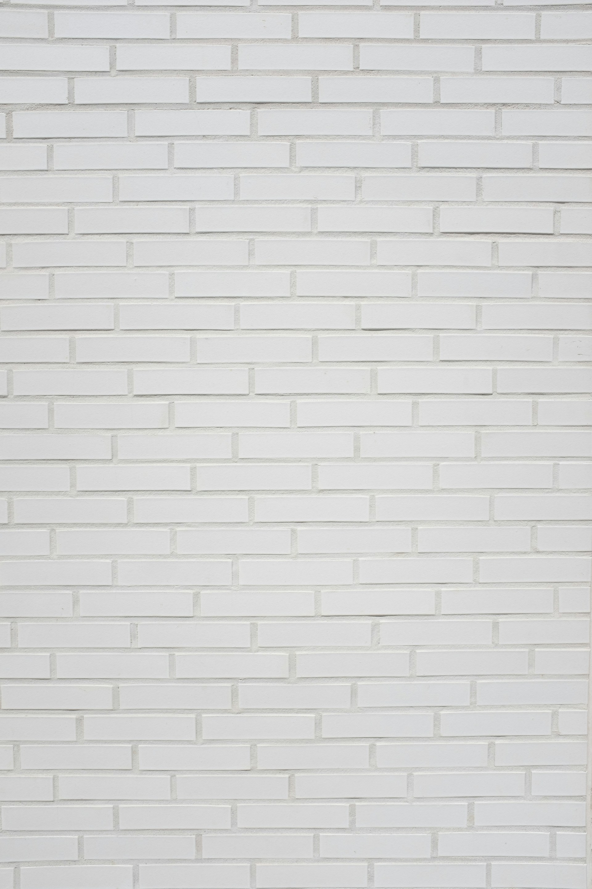 A red fire hydrant in front of a white brick wall
